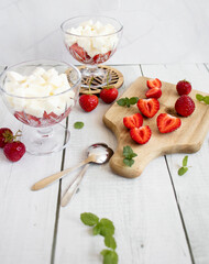 
Strawberry dessert with whipped cream and fresh strawberries. On a white wooden background