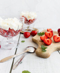 
Strawberry dessert with whipped cream and fresh strawberries. On a white wooden background
