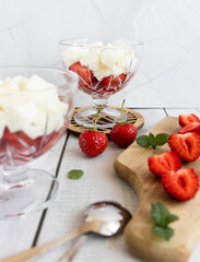 
Strawberry dessert with whipped cream and fresh strawberries. On a white wooden background