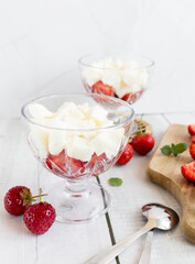 
Strawberry dessert with whipped cream and fresh strawberries. On a white wooden background