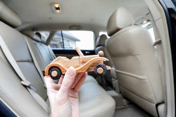 Naklejka premium A miniature wooden car against the backdrop of a real car interior.