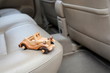 A miniature wooden car against the backdrop of a real car interior.