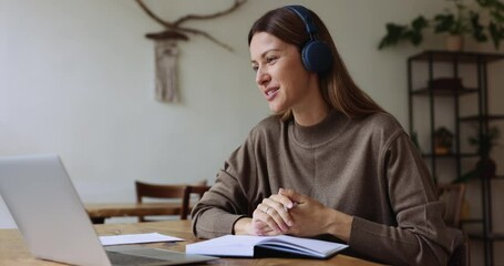 Woman talk to colleague use video call app on laptop, make notes, jotting received information in personal organizer, e-learning with help of online teacher. Virtual meeting event by business or study