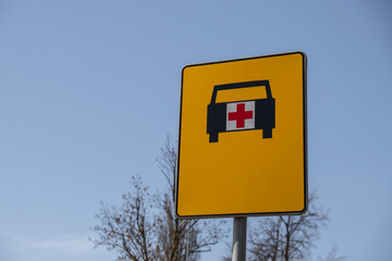 Road sign that shows way for ambulance. Ambulance yellow street sign on sky background