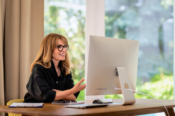 Confident woman using computer at home and having video call in office