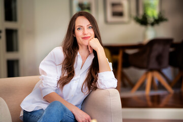 Confident young woman relaxing in an armchair in a modern home