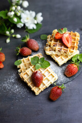 Viennese and Belgian waffles decorated with strawberries, powdered sugar and mint