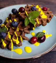 chocolate Viennese waffles and Belgian waffles with cranberries decorated with fruit topping and mint
