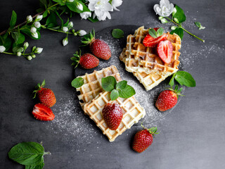 Viennese and Belgian waffles decorated with strawberries, powdered sugar and mint