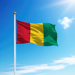 Waving flag of Guinea on flagpole with sky background.