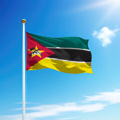 Waving flag of Mozambique on flagpole with sky background.