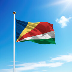 Waving flag of Seychelles on flagpole with sky background.