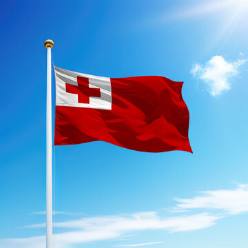 Waving flag of Tonga on flagpole with sky background.