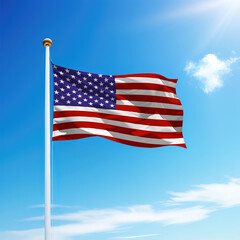 Waving flag of United States on flagpole with sky background.