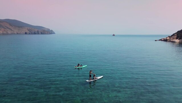 People young couples doing for water sports during summer holidays. The concept of active tourism and travel. Aerial view of people with a paddle board for support in the sea in the mountains. 4K