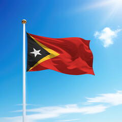 Waving flag of East Timor on flagpole with sky background.