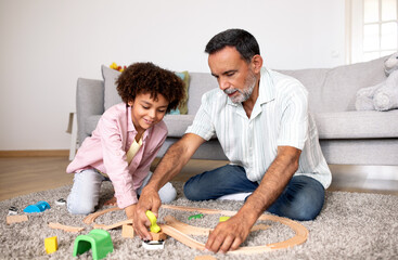 Fototapeta premium Latin Grandpa And Grandson Playing With Toys In Living Room