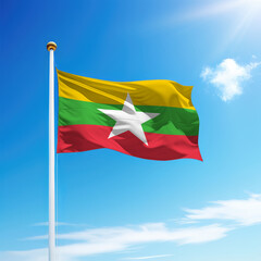 Waving flag of Myanmar on flagpole with sky background.