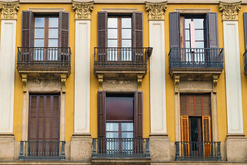 Wooden windows with shutters on yellow walls. Facade of a European antique city building.