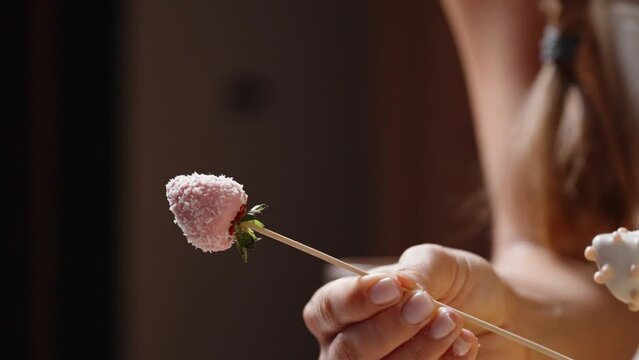The strawberries dipped in pink chocolate are shaken to remove any excess coconut flakes and placed alongside the ready ones.
