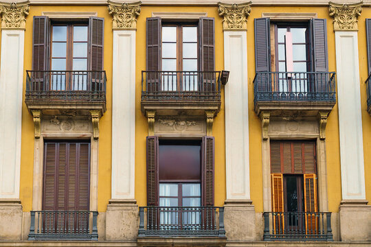 Wooden Windows With Shutters On Yellow Walls. Facade Of A European Antique City Building.