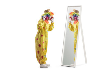 Clown in a yellow costume standing in front of a mirror