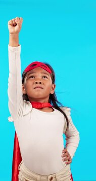 Girl, superhero costume and hand up to fly, play and fantasy with fun imagination and courage in studio. Super power, kids cosplay and child in cape, mask and hero character games on blue background.