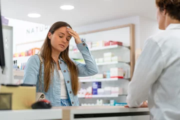 Aluminium Prints Pharmacy Young woman with a headache in a pharmacy