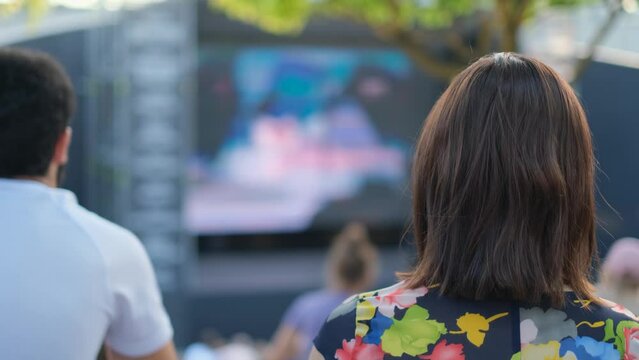 Spectators watch a movie in a street cinema