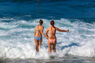 summer beach two girl friends with bikini hands by hands into the sea water crete greece