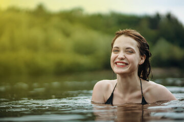 Fototapeta premium beautiful smiling woman bathes in the water of the lake, sea river. The concept of a happy vacation at sea.