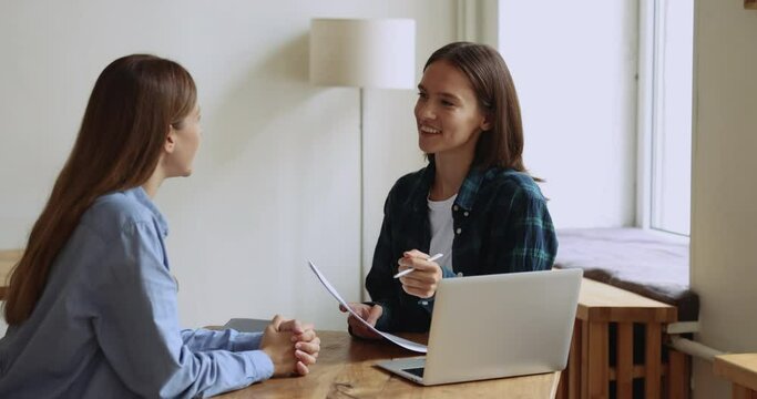 HR manager holds CV resume interviewing to female applicant, sit together at desk met in modern office. Recruiter listen to skilled job candidature, examining, ask questions. Human resources, staffing