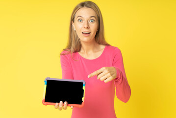 beautiful young woman shows tablet pc with black screen. Portrait of astonished blond woman in red...