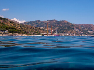 Fototapeta premium Barca a vela nella baia dell'isola di Sirene a Taormina