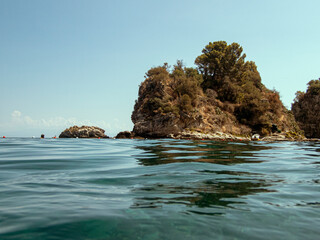 Costa rocciosa dell'Isola delle Sirene nel Mar Jonio in una soleggiata giornata estiva
