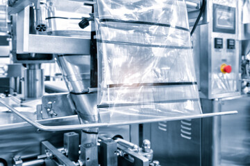 Automatic industrial machine for plastic packaging with light effect of products and food. shaft of an automated packaging line with plastic film in a light blue scene. product packaging concept