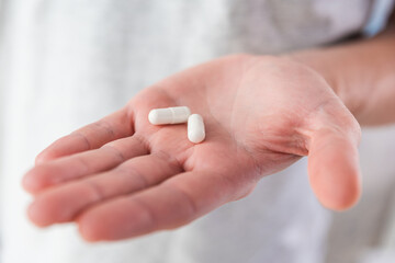 White capsules with collagen in male hand. Nutritional supplement, medicine, drug for joints...