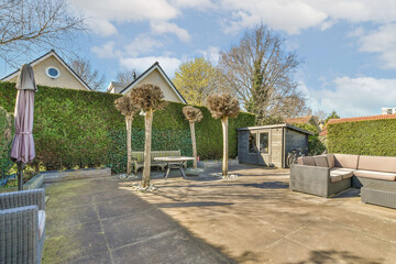 Fototapeta premium a backyard area with furniture and trees in the back yard, surrounded by lush green bushes on either side of house