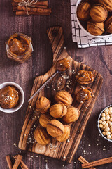 Fresh nut shaped cookies filled with boiled condensed milk on a board top and vertical view