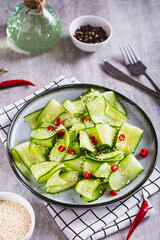 Fresh salad of cucumbers, hot red pepper and sesame seeds on a plate vertical view