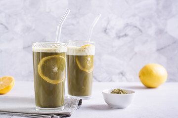 Refreshing matcha tea with lemon in glasses with straws on the table