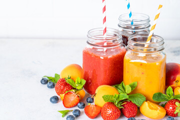 Smoothie with fresh fruits and berries at white background. Smoothie set in jars.