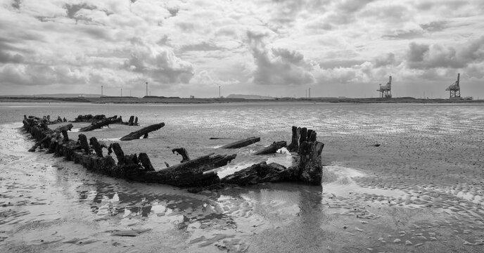 Monochrome image od boat wreck embeeded in sand at low tide