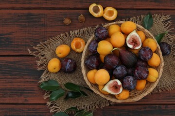 Fruits in a basket, figs, apricots, plums, on a wooden table, top view, background image, for presentations