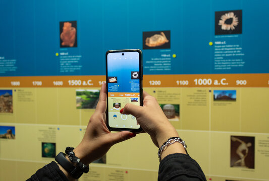 BOGOTA, COLOMBIA Closeup to a woman hands holding a smartphone taking a picture to a history timeline into colombian golden museum