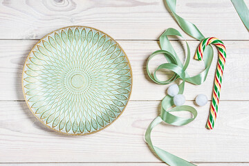 Empty light green plate, lollipop and decorations shot from above (top view, flat lay). Background layout with copy space.