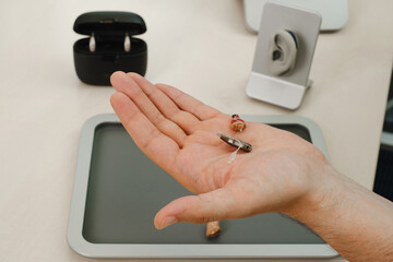 Modern miniature hearing aids. Small and discreet invisible hearing aids in hands. Closeup of...