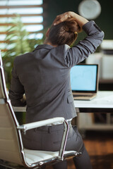 business owner woman in green office stretching neck