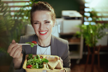 smiling bookkeeper woman in green office eating salad