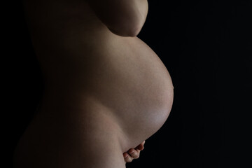 Midsection of unrecognizable standing naked woman with very round pregnant baby bump. Final month...